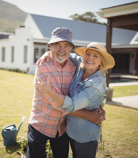Senior couple embracing in front of their home